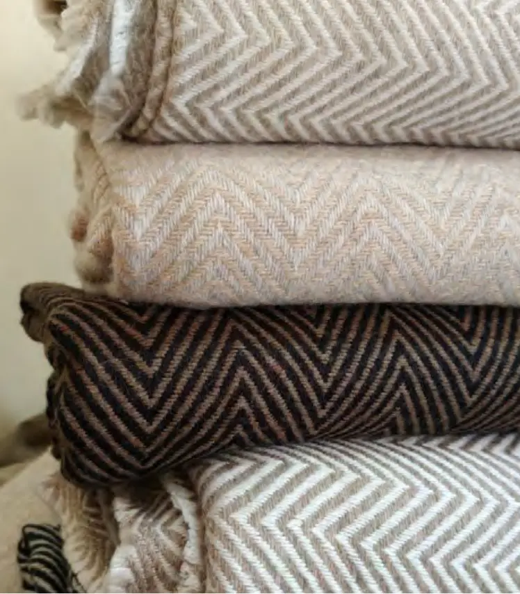 Stack of light and dark cashmere throws with herringbone weave