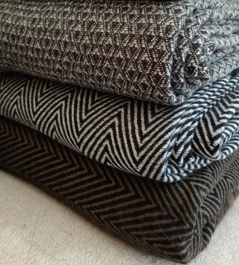 Close-up of folded natural wool shawls with a herringbone weave